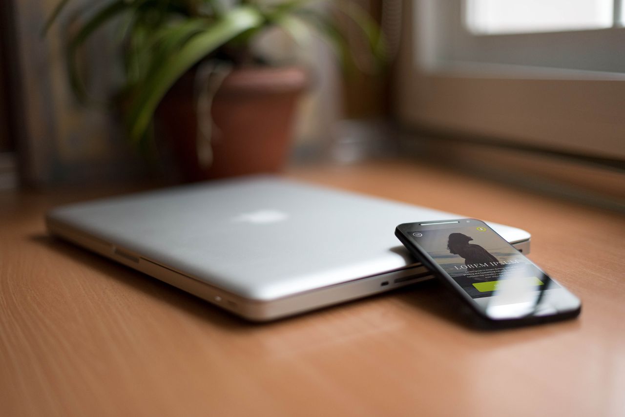 services-04 Close-up of a silver laptop and smartphone on a wooden desk, capturing modern work essentials.